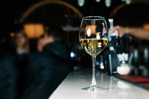 Стакан белого вина крупным планом на барной стойке