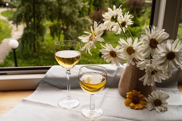 Glass of white wine and garden flowers over green garden background,outdoor.