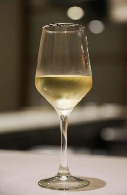 A glass of white wine is sitting on a table.