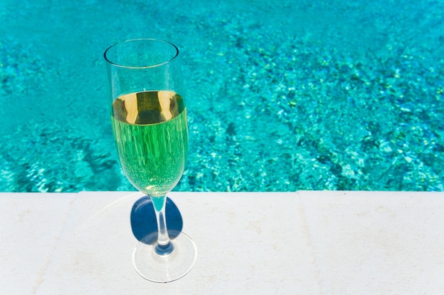 Photo glass of white wine on pool board outdoor