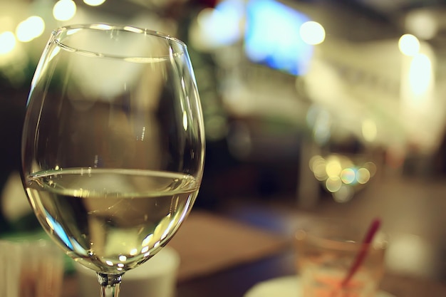 Glass white wine restaurant interior, abstract evening dinner\
with alcohol at the bar