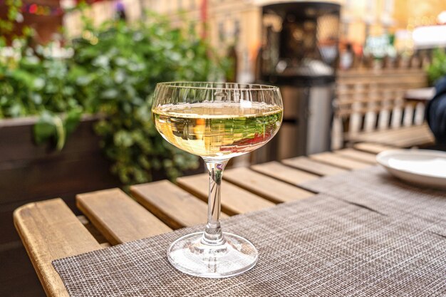 A glass of white wine standing on a table in a cafe outdoors