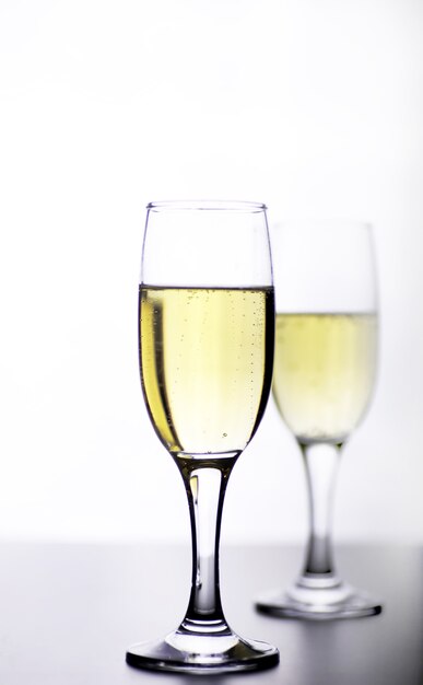 白い背景の分離のテーブルの上の白ワインのガラス