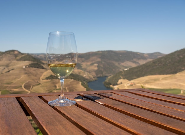 Glass of white wine for tasting above the hillsides of the Douro valley in Portugal