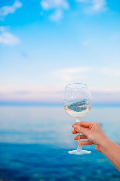 Glass of white wine on tropical beach on the sunset