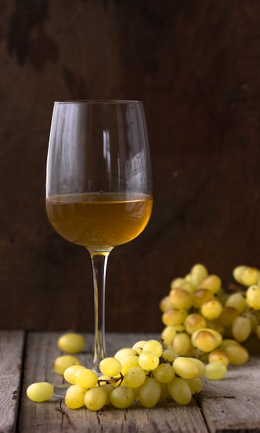 Glass of white wine in wine cellar. Old white wine on wood.