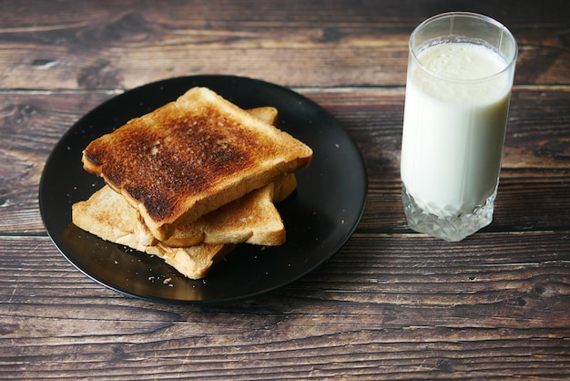 Glass of whole cream milk and bread on table
