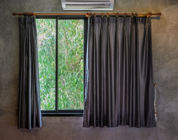 Glass window with open curtain and green garden on background