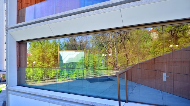 a glass window with a reflection of trees and a building with a house in the background