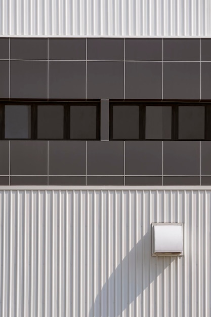 Photo glass windows with dryer vent on white corrugated metal wall of modern industrial building