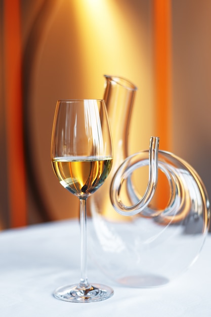 Glass of wine and a decanter on a table with a white tablecloth.