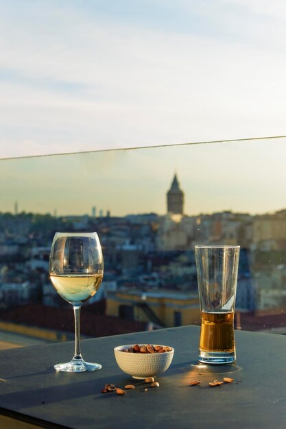 A glass of wine and a glass of wine sit on a table with a view of the city in the background.