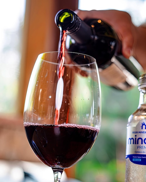 A glass of wine is being poured into a glass with the word minot on it.