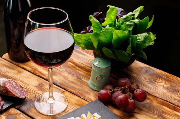 Glass of wine and meat slicing on wooden table close up