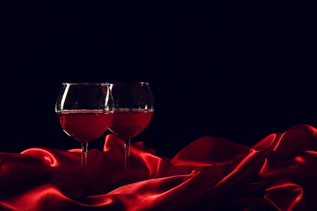 Glass of wine on red silk with dark surface