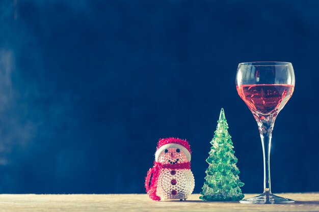 木製のテーブル、黒の背景にクリスマスの装飾とワインのガラス