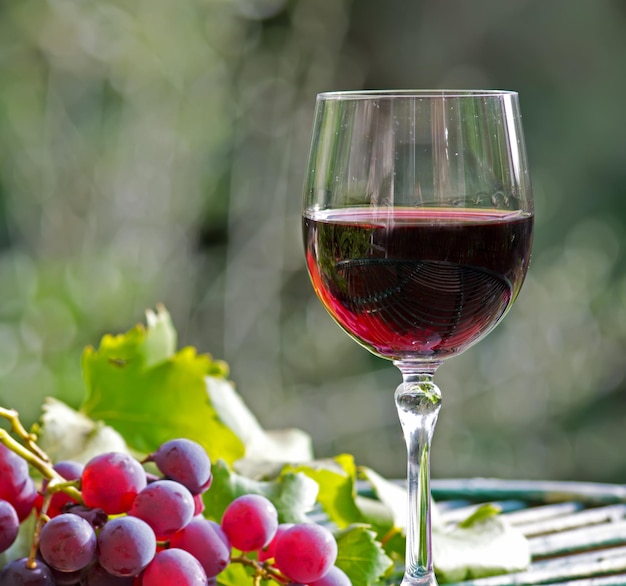 Glass of wine with grapes and leaves on a wooden table