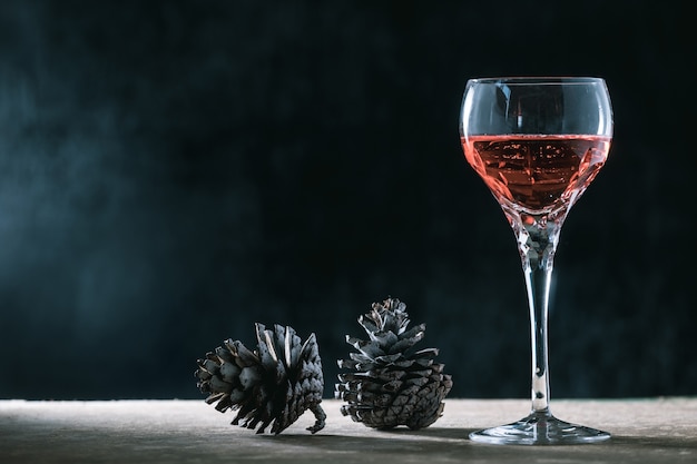 Glass of wine with pine cones on the wooden table