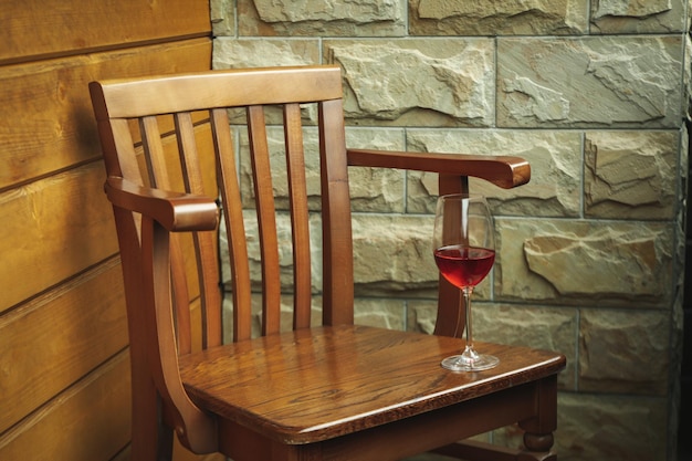 Glass of wine on wooden chair on balcony