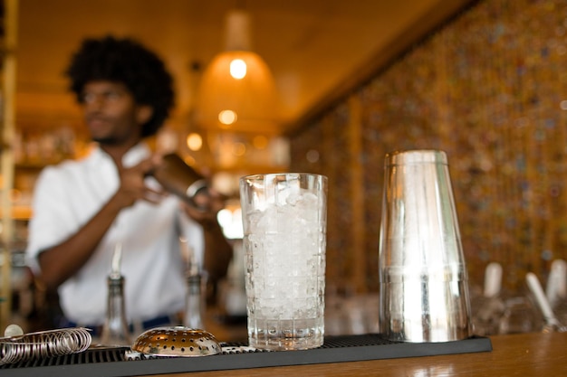 Glass with bartender behind it preparing a cocktail