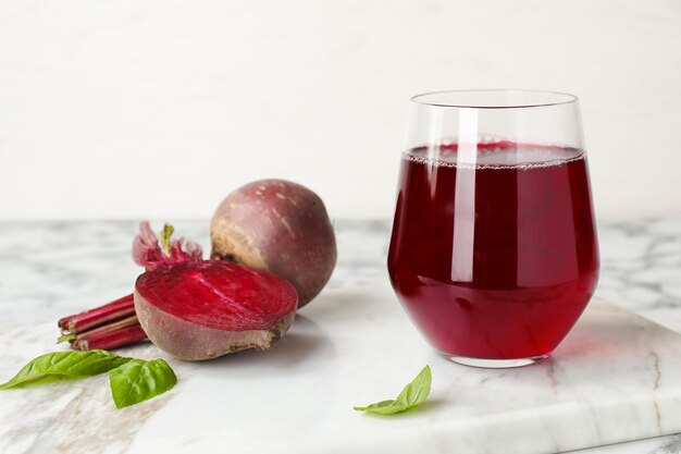 Glass with beet juice and fresh vegetable on table