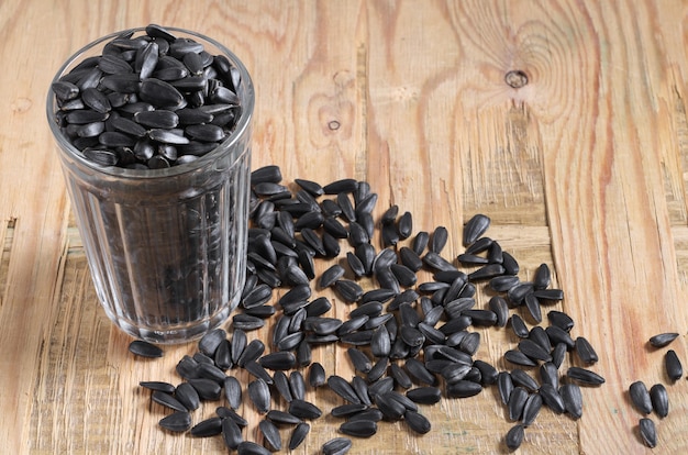 Glass with black sunflower seeds on an old wooden background