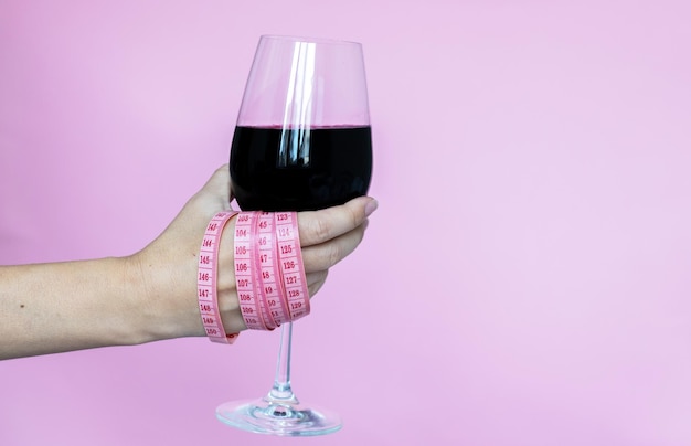 女性の拳の周りにシャンパンまたはワインのメジャー テープが付いたグラス