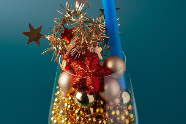 Glass with Christmas decorations on dark green background