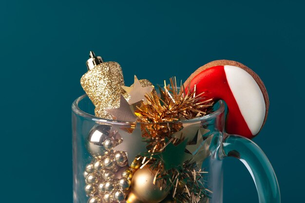 Glass with Christmas decorations on dark green background