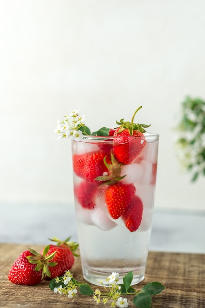 Photo glass with clear carbonated drink, ice and strawberries