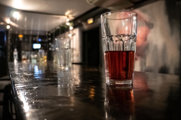 glass with dark alcoholic drink on the bar counter