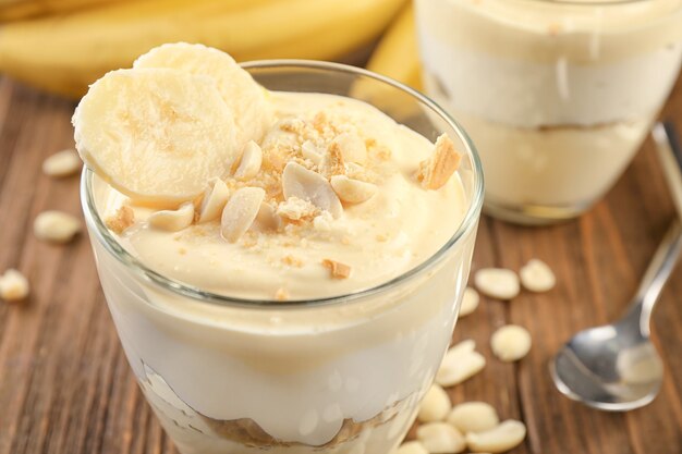 Glass with delicious banana pudding on table