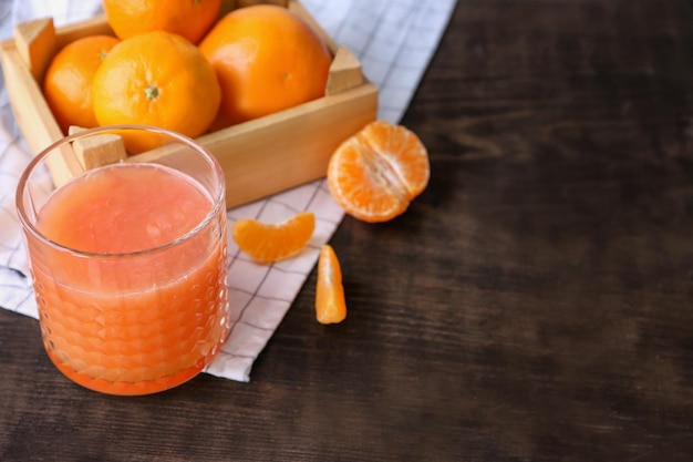 Glass with delicious citrus juice and fresh tangerines on table