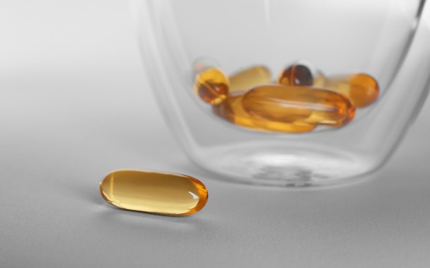 Photo glass with fish oil capsules on grey background