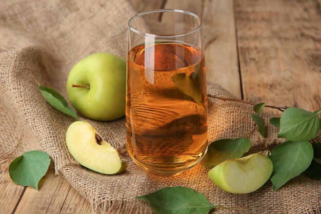 Glass with fresh apple juice on wooden table