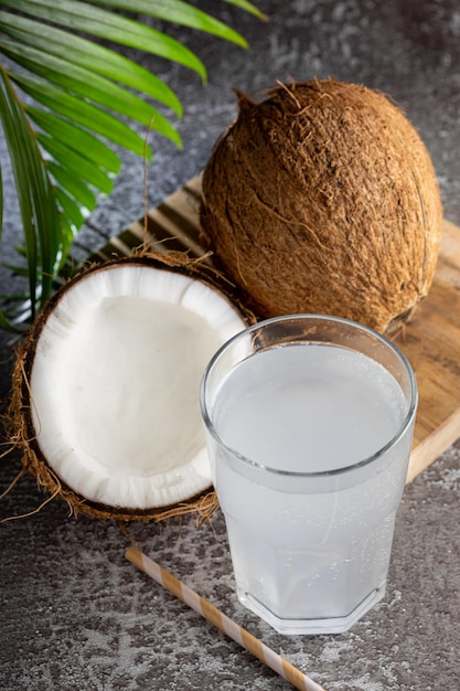 Glass with fresh coconut water and coconuts on the table