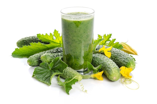 Glass with green smoothie and cucumbers flowers leaves isolated on white