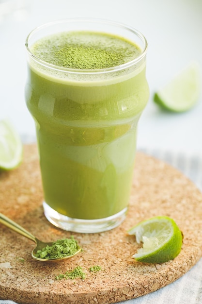 A glass with a green smoothie with banana oat milk lime and matcha tea The concept of vegetarian and healthy diet food