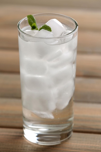 Glass with ice cubes on wooden table