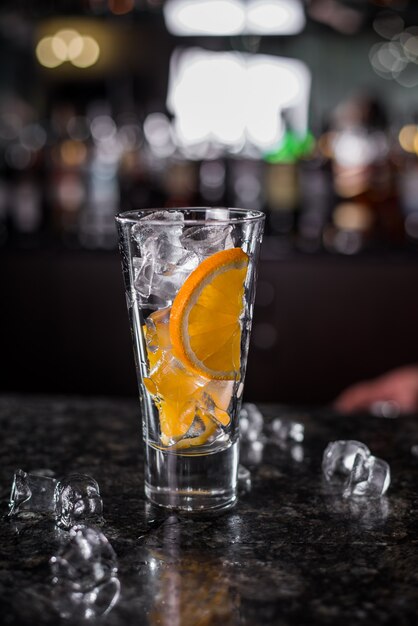 glass with ice and orange slices coctail pretairing at the bar