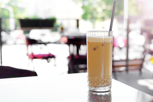 A glass with latte and black straws stands on a table with a metal coating on the summer terrace of a cafe Horizontal photo