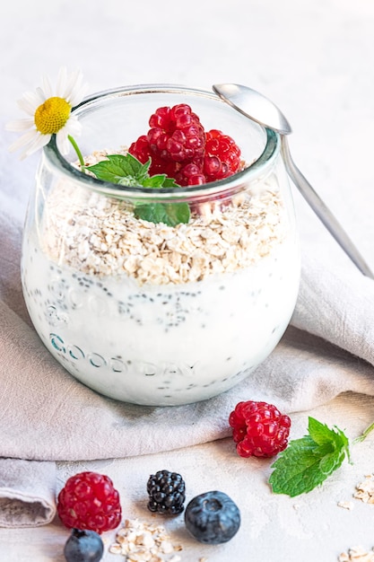 Un bicchiere con strati di yogurt ai semi di chia avena e frutti di bosco servito a colazione