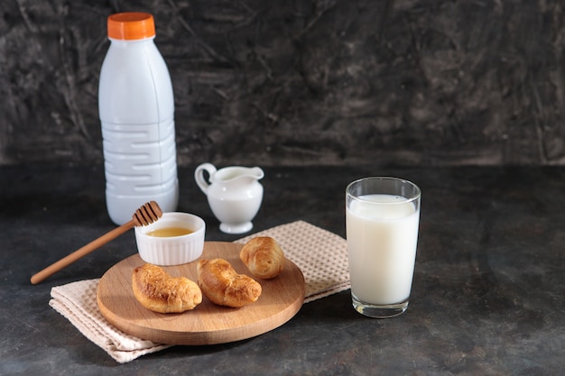 Glass with milk and croissants with honey on a black background. Tasty french breakfast. Dessert. Space for text