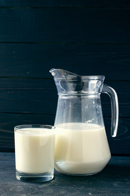 Photo a glass with milk and a pot on a dark background