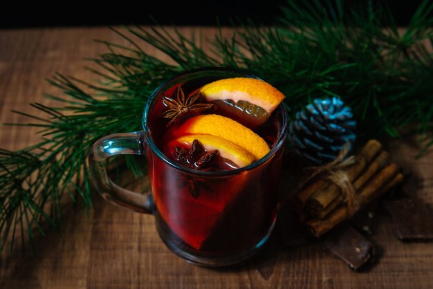 전나무 가지 새 해 나무 테이블에 mulled 와인 유리. 전통적인 뜨거운 겨울 음료와 함께 크리스마스 장식