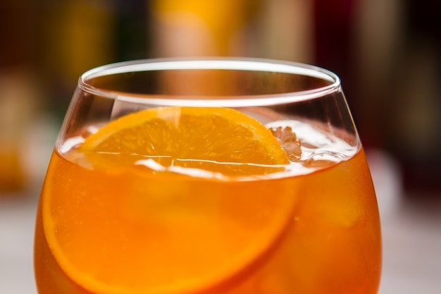 Стакан с апельсиновым напитком. Долька свежего апельсина. Aperol spritz подается в ночном клубе. Спирт и газированная вода.