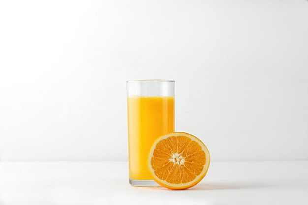 메뉴를 위해 흰색 테이블에 오렌지 주스와 신선한 과일을 넣은 유리와 조롱. 쉬운 격리.