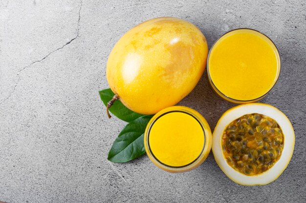 Glass with passion fruit juice and sliced passion fruit on the table