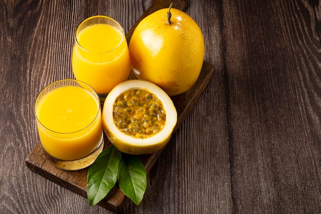 Glass with passion fruit juice and sliced passion fruit on the table