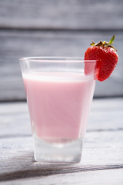 Vetro con fragola liquida rosa su un cocktail di vetro di latte e fragole bevanda densa e dolce